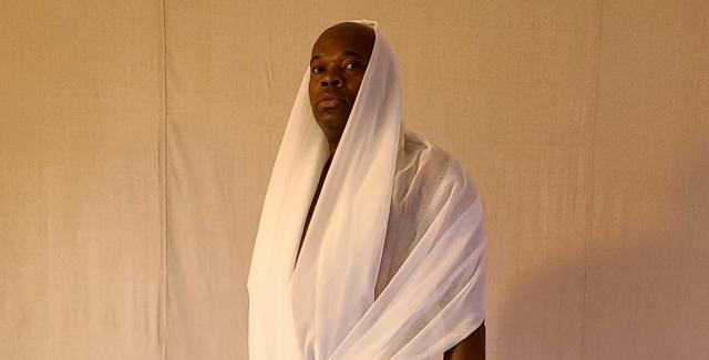 A Black person is wrapped in a white sheer fabric.