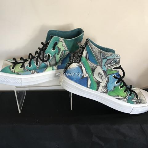 A pair of high top sneakers embellished with a graphic design using blue, green, black and grey colors.