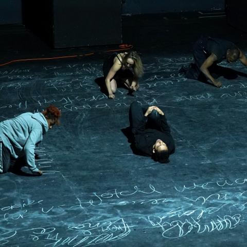 Four dancers perform on the floor of the stage.