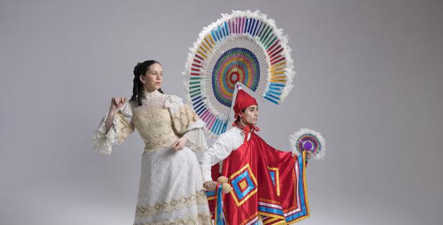 A man and a woman pose in traditional Mexican garb in a white walled studio space