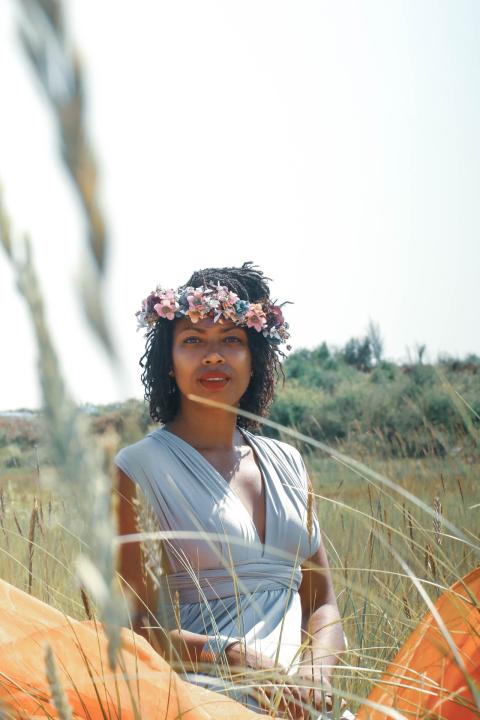 Jenny, in a floral headress, smiles behind grains that are out of focus in the foreground.