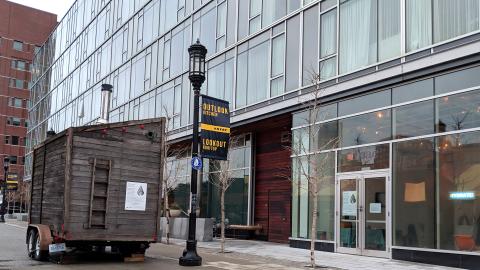 A small wooden lodge, sweatbox, is parked on street next to the Envoy Hotel