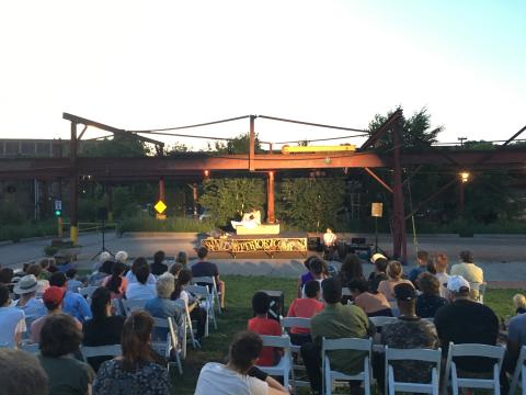 A crowd watches a performance under some steel beams.