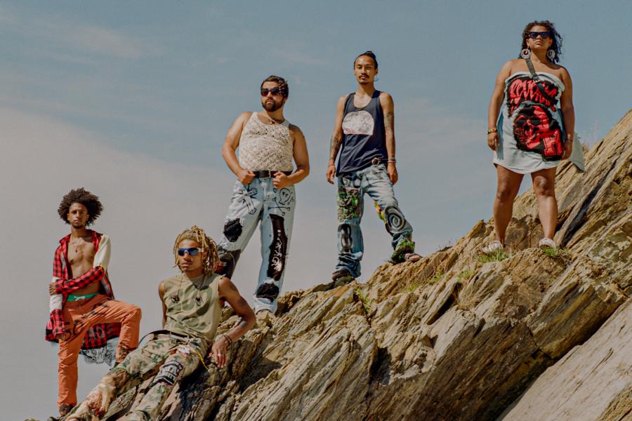 Five folks, in sunglasses, pose over rocks.