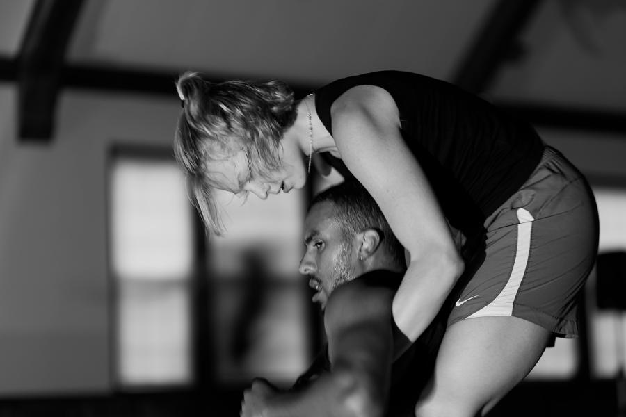 In black and white, a white lady drags a Black man from under his armpits.