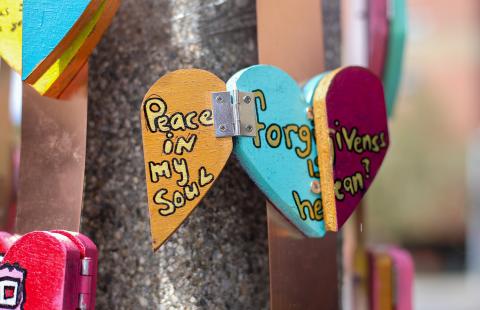 Foldable heart sculptures with sayings (like "peace in my soul") are wrapped around a pole on a street corner.