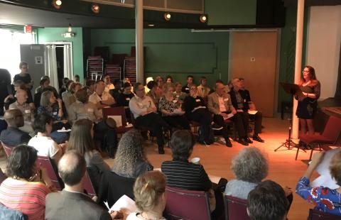 A woman with a music stand presents at a meeting