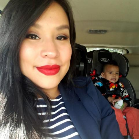 A selfie of Endawnis, with her son in a carseat behind her.