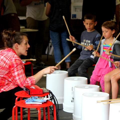 Maria teaches three kids how to use buckets as drums.