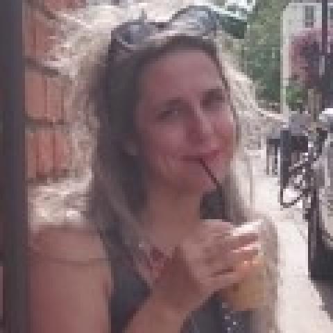 Karen sips iced coffee and smiles on a street corner
