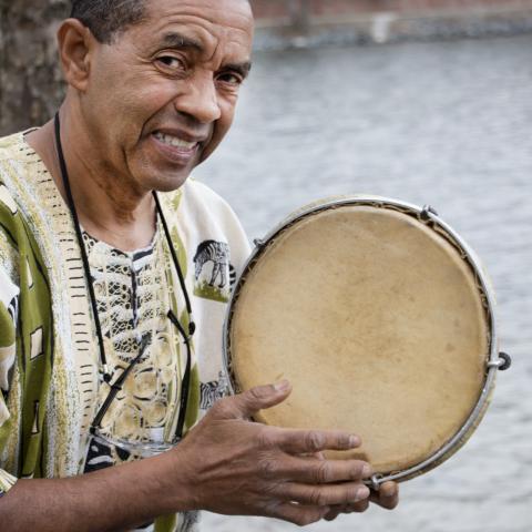 Jorge smiles with a tambourine by Jamaica Pond