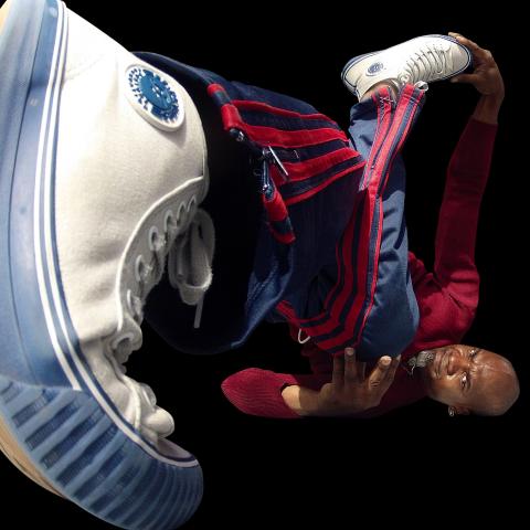 With the lens by the bottom of a Raphel's shoe lifted off the ground in the foreground as he break dances