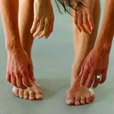 Four sets of hands hang over a pair of legs and feet.