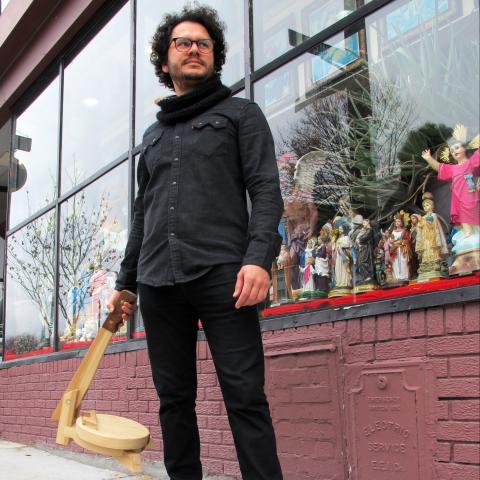 Salavador poses in front of a store front with Christian figurines.