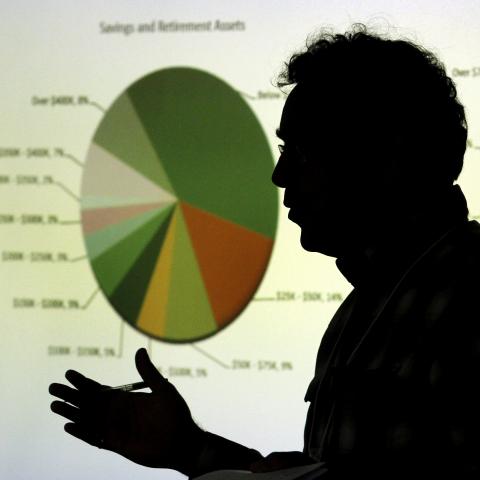 Silhouette of a man giving a presentation in front of a projection of pie charts/graphs.