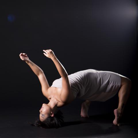 A dancer rests on their head and feet, with their torso extended.