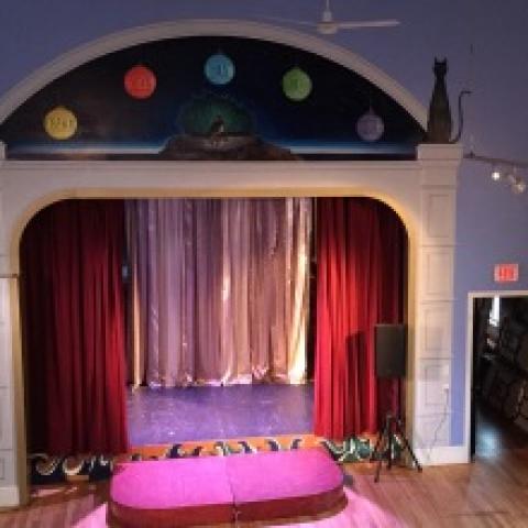 a cute proscenium stage in a giant purple room